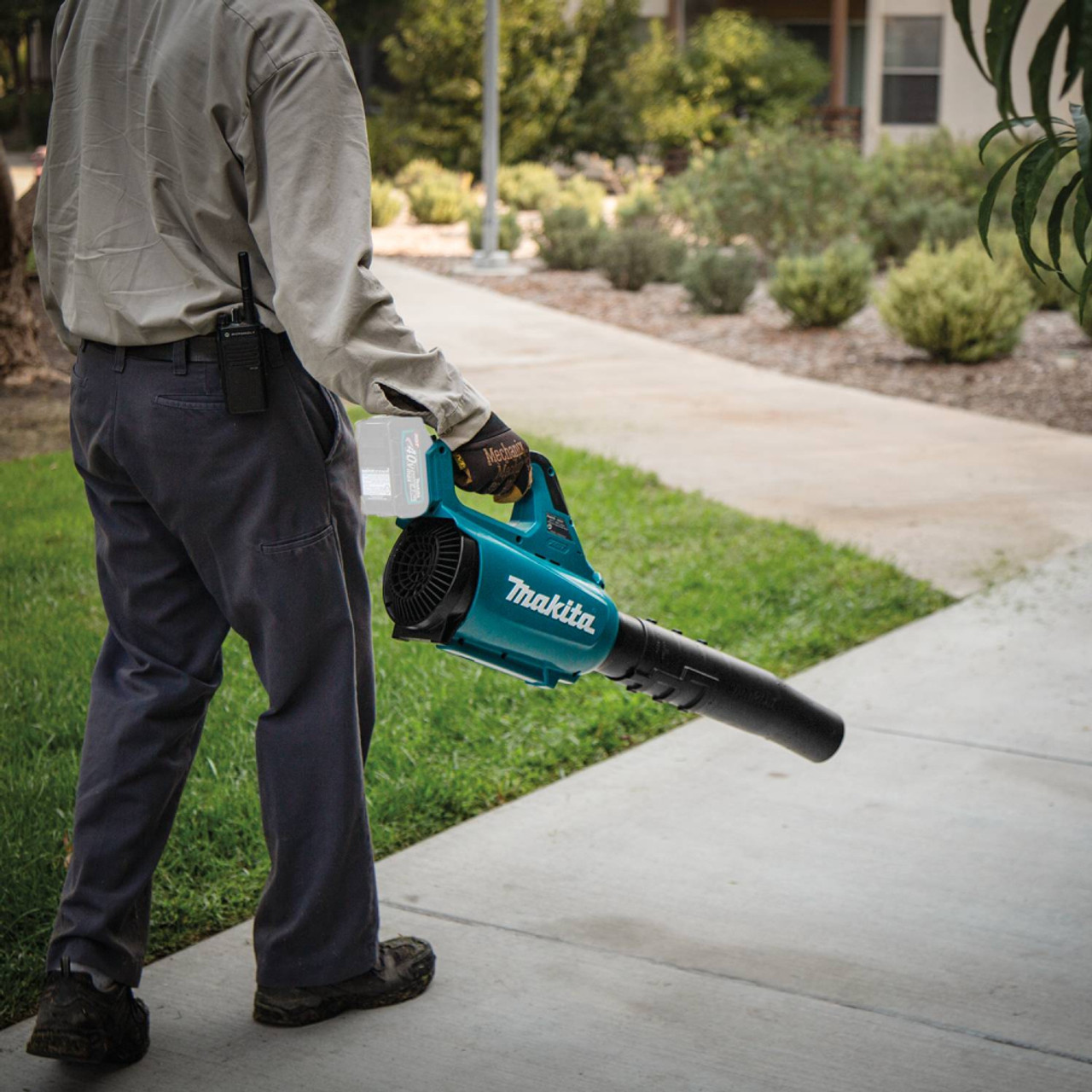 Makita UB001GZ 40V MAX XGT Cordless Brushless Turbo Blower (Tool Only) showing in use blowing debris off of a side walk Makita UB001GZ 40V MAX XGT Cordless Brushless Turbo Blower (Tool Only) showing in use blowing debris off of a side walk