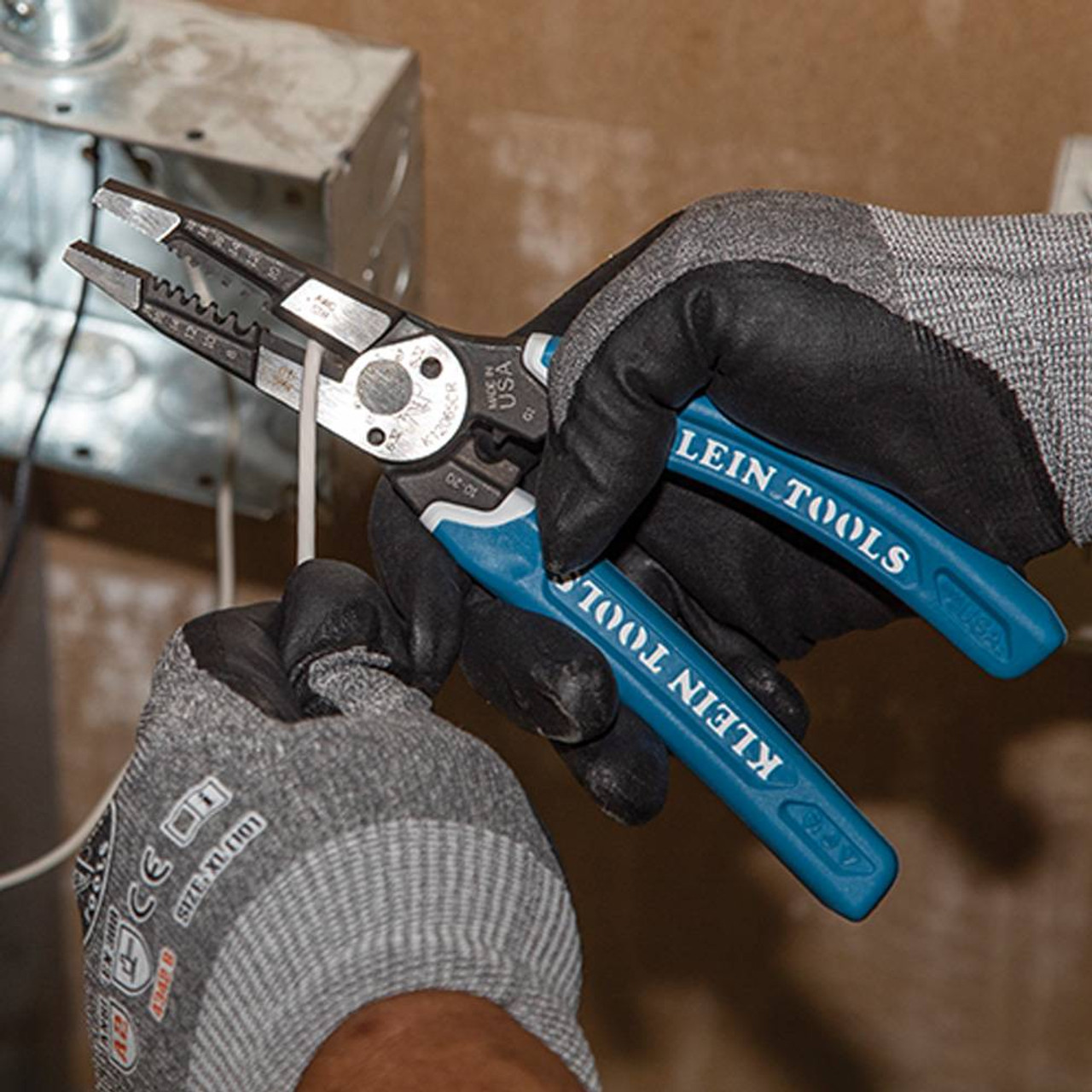 Klein Tools K12065CR Klein-Kurve Heavy-Duty Wire Stripper / Cutter / Crimper Multi Tool showing in use cutting electrical wires Klein Tools K12065CR Klein-Kurve Heavy-Duty Wire Stripper / Cutter / Crimper Multi Tool showing in use cutting electrical wires