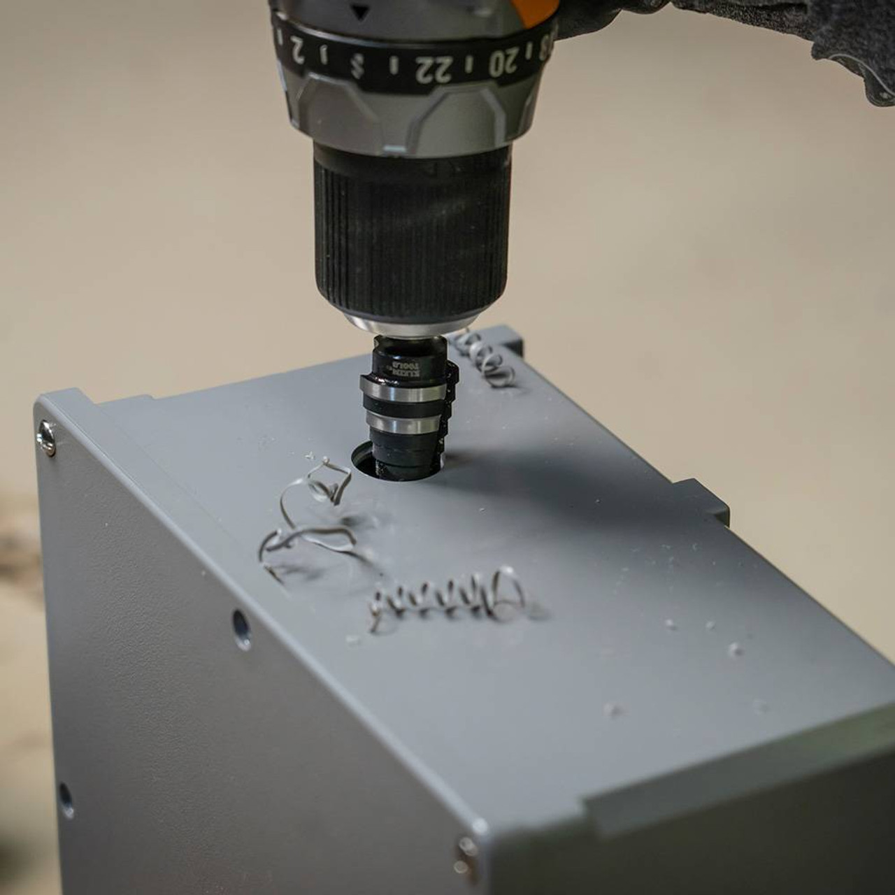 Klein Tools KTSB14 #14 12-Step 3/16-inch to 7/8-inch Double-Fluted High-Speed Step Drill Bit showing in use showing in use drilling into an electrical junction box Klein Tools KTSB14 #14 12-Step 3/16-inch to 7/8-inch Double-Fluted High-Speed Step Drill Bit showing in use showing in use drilling into an electrical junction box