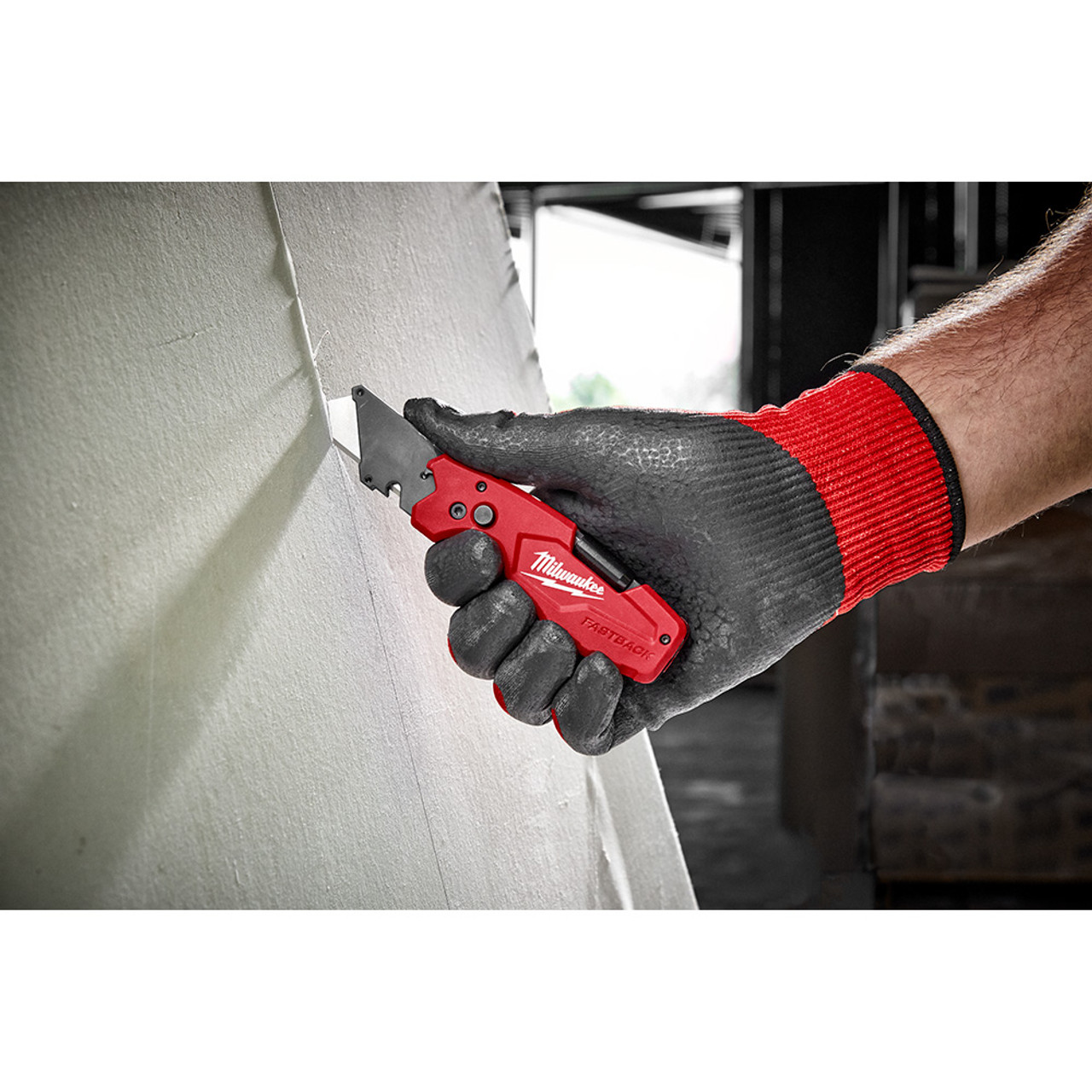 Milwaukee 48-22-1505 FASTBACK 6-In-1 Folding Utility Knife showing in use cutting sheet of drywall Milwaukee 48-22-1505 FASTBACK 6-In-1 Folding Utility Knife showing in use cutting sheet of drywall