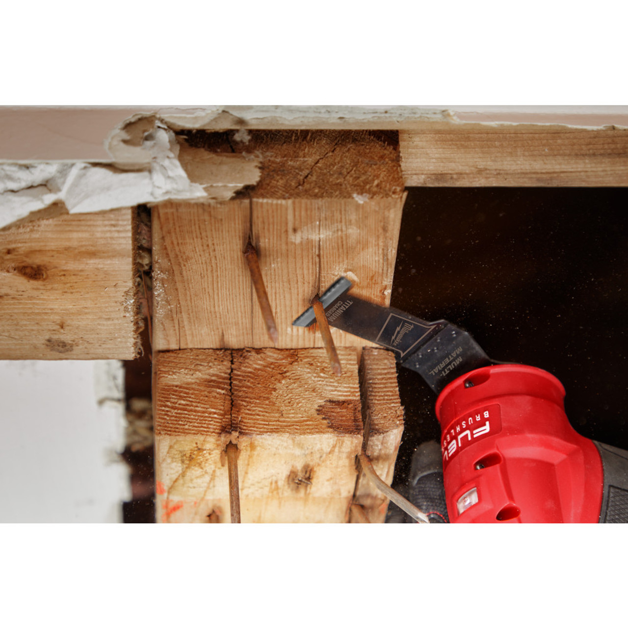 Milwaukee 49-25-1233 OPEN-LOK 1-3/8-inch Universal Fit Titanium Enhanced Bi-Metal Multi-Material Cutting Multi-Tool Oscillating Blades - 3pk showing in use cutting nail sticking out of a frame beam Milwaukee 49-25-1233 OPEN-LOK 1-3/8-inch Universal Fit Titanium Enhanced Bi-Metal Multi-Material Cutting Multi-Tool Oscillating Blades - 3pk showing in use cutting nail sticking out of a frame beam