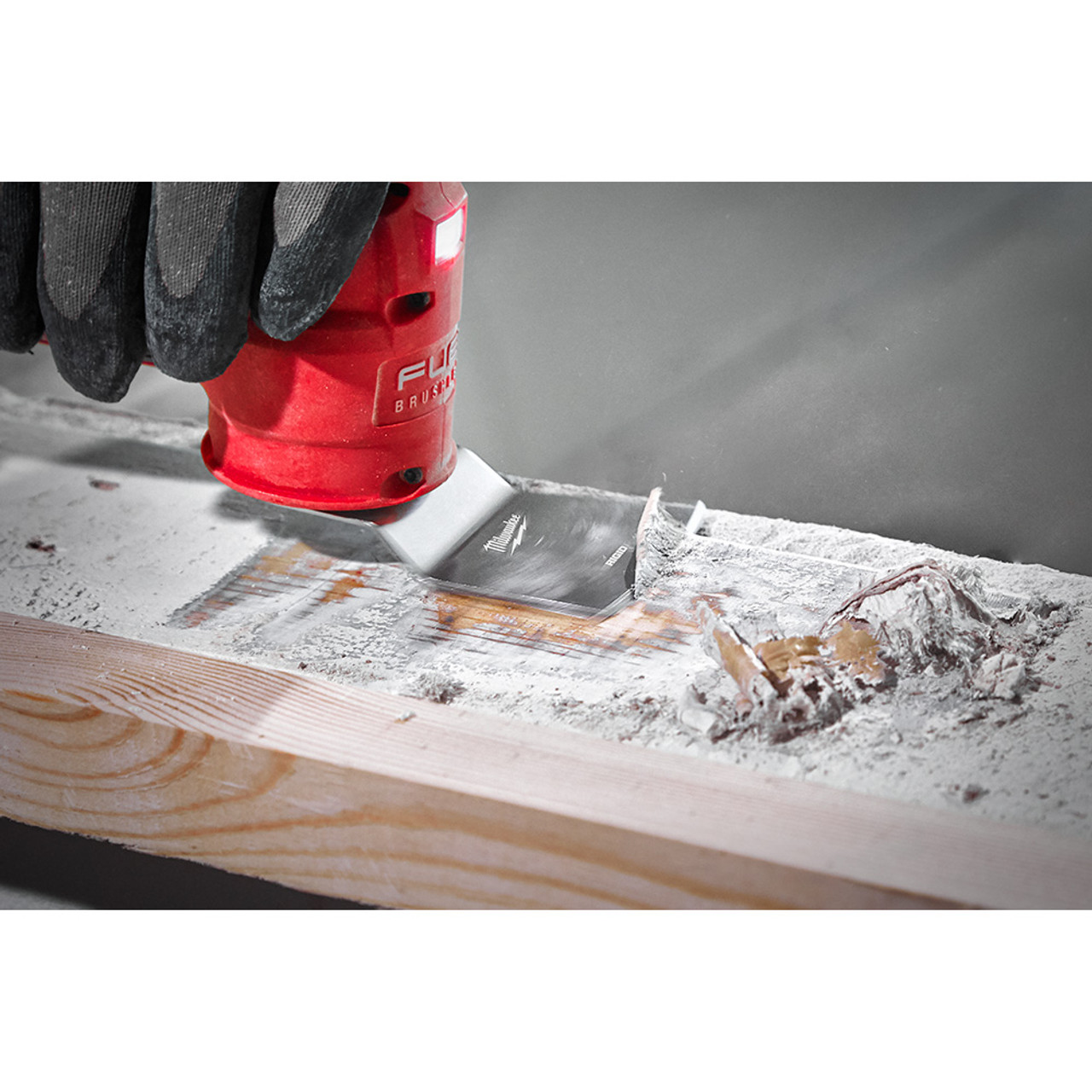 Milwaukee 49-25-2202 OPEN-LOK 2pc 2-inchUniversal Fit Rigid & Flexible Multi-Tool Oscillating Scraper Set showing flexible scraper scraping paint off of a 2X4 dimensional lumber Milwaukee 49-25-2202 OPEN-LOK 2pc 2-inchUniversal Fit Rigid & Flexible Multi-Tool Oscillating Scraper Set showing flexible scraper scraping paint off of a 2X4 dimensional lumber