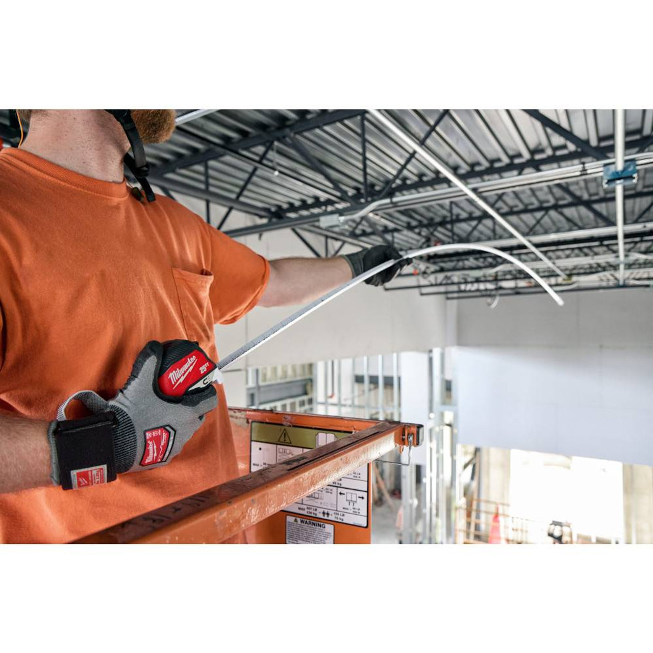 Milwaukee 48-22-1027M 25' Electrician's Magnetic Tape Measure showing in use measuring the distance of an area using the standout Milwaukee 48-22-1027M 25' Electrician's Magnetic Tape Measure showing in use measuring the distance of an area using the standout