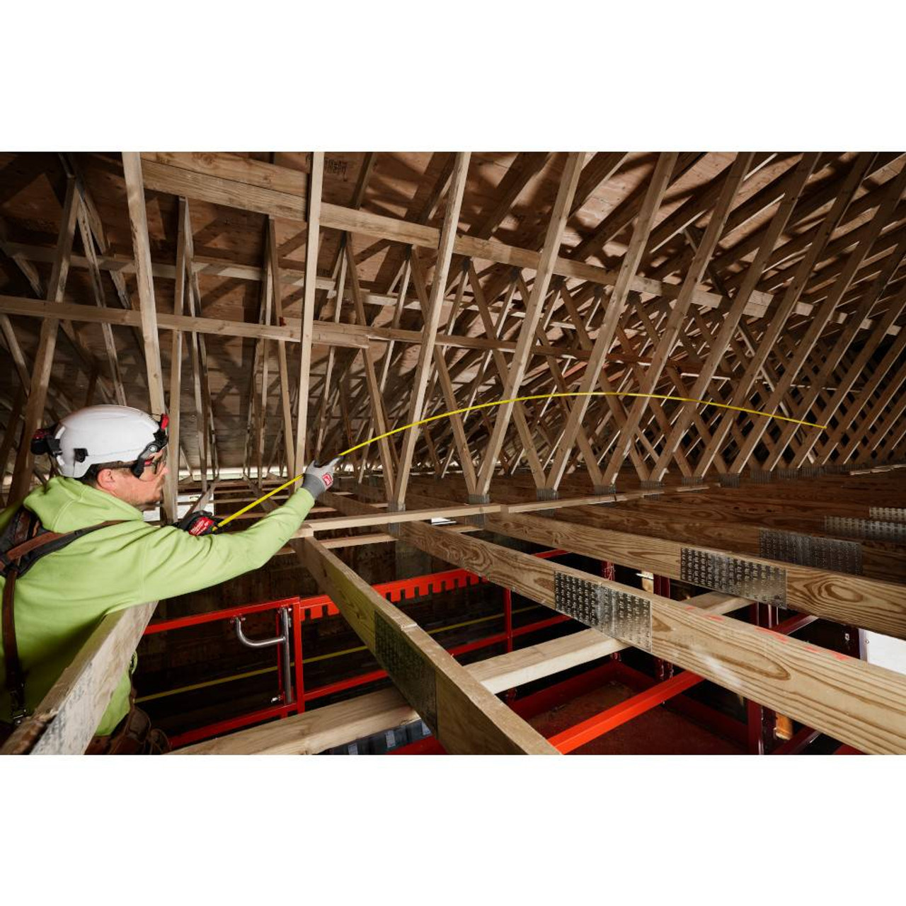 Milwaukee 48-22-1225M 25' Wide Blade Magnetic Tape Measure showing in use measuring the distance between roof rafters Milwaukee 48-22-1225M 25' Wide Blade Magnetic Tape Measure showing in use measuring the distance between roof rafters