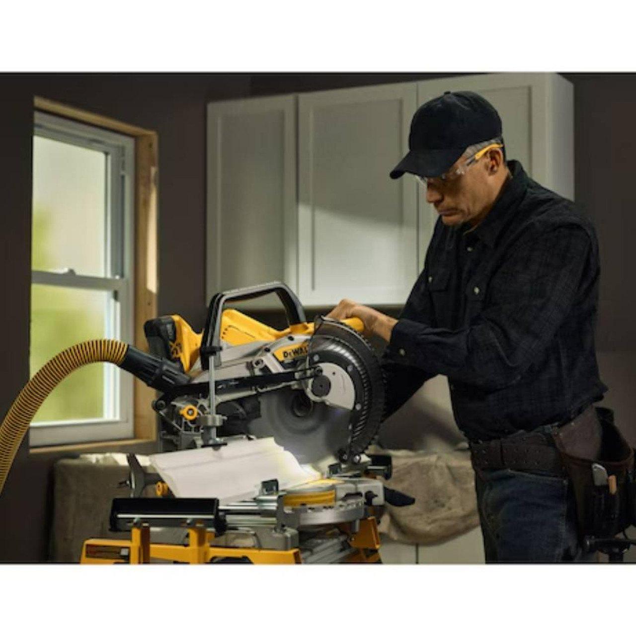 DeWalt DCS714WW1 20V MAX XR Cordless 10in Double Bevel Fixed Mitre Saw Kit showing in use cutting moulding with saw mounted on stand with vacuum attached (Battery, stand, and vacuum sold separately)
