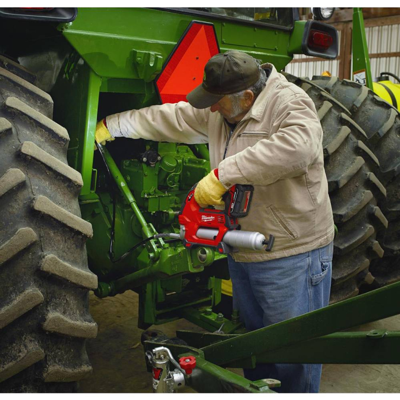 Milwaukee 2646-22CT M18 Cordless 2-Speed Grease Gun Kit showing in use lubricating tractor joints