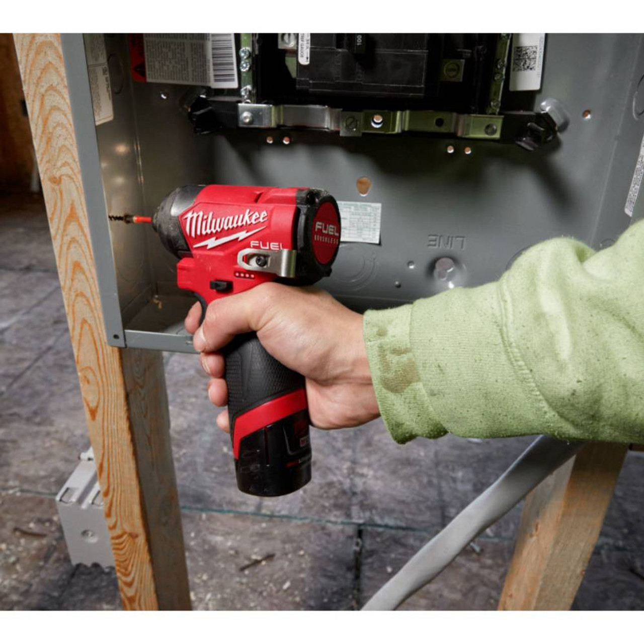 Milwaukee 3453-22 M12 FUEL 1/4 inch Hex Impact Driver Kit showing in use driving a screw to mount an metal box to a wood stud