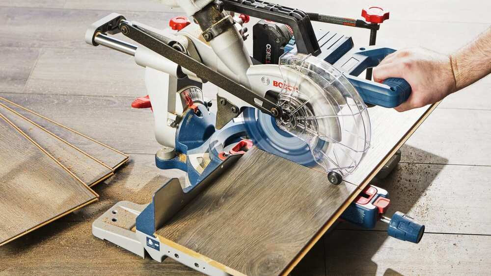 Bosch GCM18V-07SN14 PROFACTOR 18V Cordless Brushless 7-1/4in Single-Bevel Slide Mitre Saw Kit showing in use making a cross cut through laminate flooring