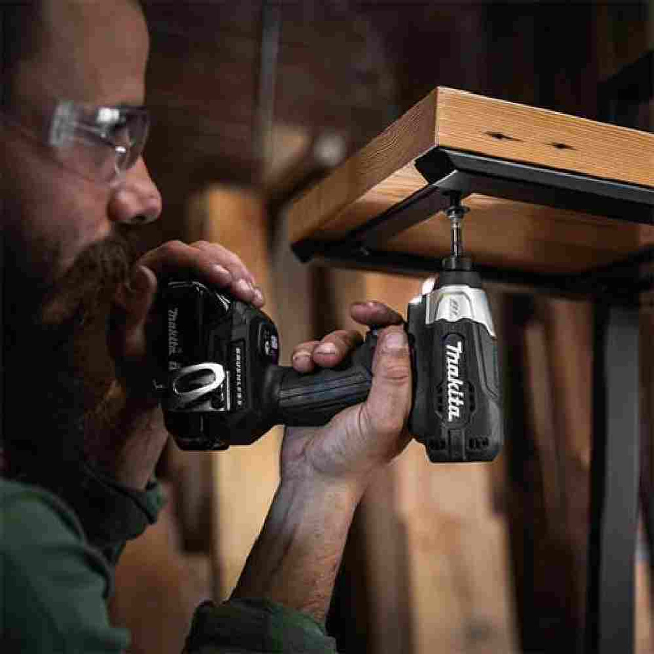 Makita DTD157ZB Impact driver driving a fastener vertically upwardly through a metal brace into wood.