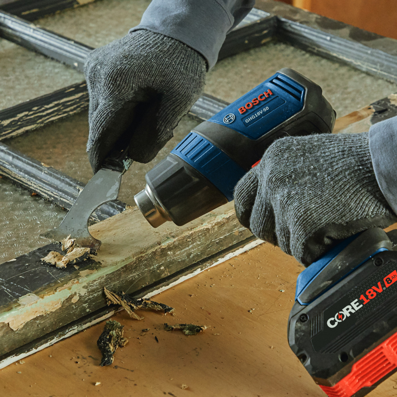 Bosch GHG18V-50N 18V Cordless Heat Gun (Tool Only) showing in use heating old paint to remove it from wood frames