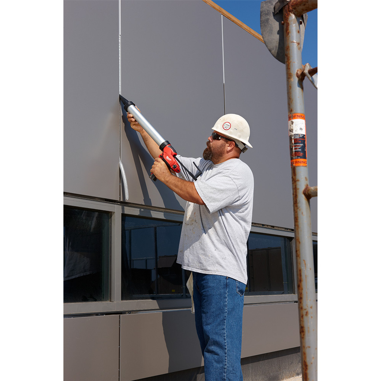 Milwaukee 2442-21 M12 20oz Aluminum Sausage Style Caulking Gun showing in use sealing between wall panels