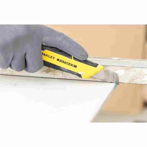 Stanley FMHT10329 FATMAX Ergonomic-Grip 18mm Snap-Off Blade Knife showing in use cutting through sheet marital with edge guide