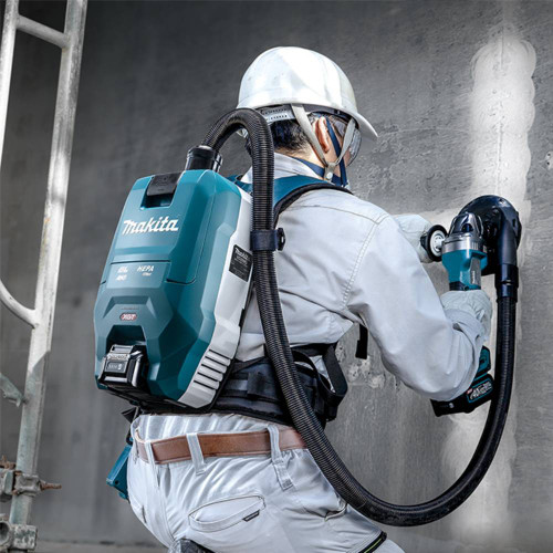 Makita VC009GZ02 40V XGT Brushless 2 L Backpack Vacuum Cleaner (Tool Only) showing in use attached to a grinder collecting shavings (Battery and Tool sold separately)