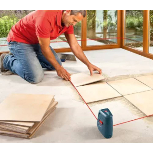 Bosch GLL 3-15 50' Self-Leveling Three-Line Line Laser Kit showing in use aligning tile on the floor