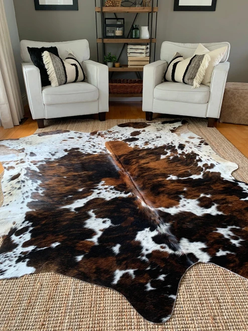 Brown and white cowhide rug in modern living room with armchairs, perfect for home decor and flooring.