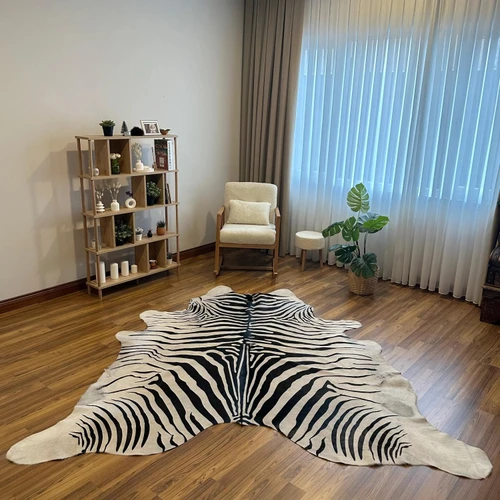 Zebra print cowhide rug on hardwood floor in modern living room, natural animal hide decor