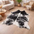 Black and white cowhide rug in modern living room with wood floors and cozy decor