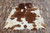 Brown and white cowhide rug on wooden floor, premium animal hide for crafts and decor