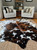 Brown and white cowhide rug in modern living room with armchairs, perfect for home decor and flooring.