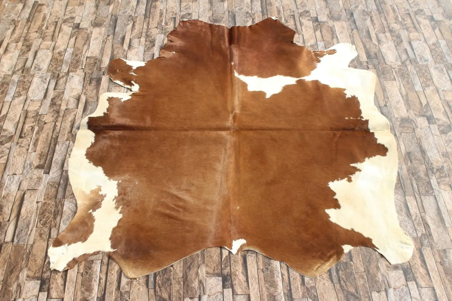 Brown and white cowhide rug on tiled floor, premium animal hide for home decor or crafting