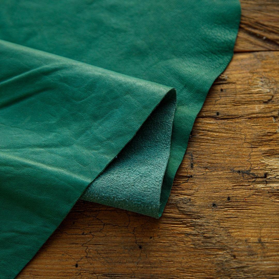Rich green leather hide on rustic wood, ideal for crafts and upholstery