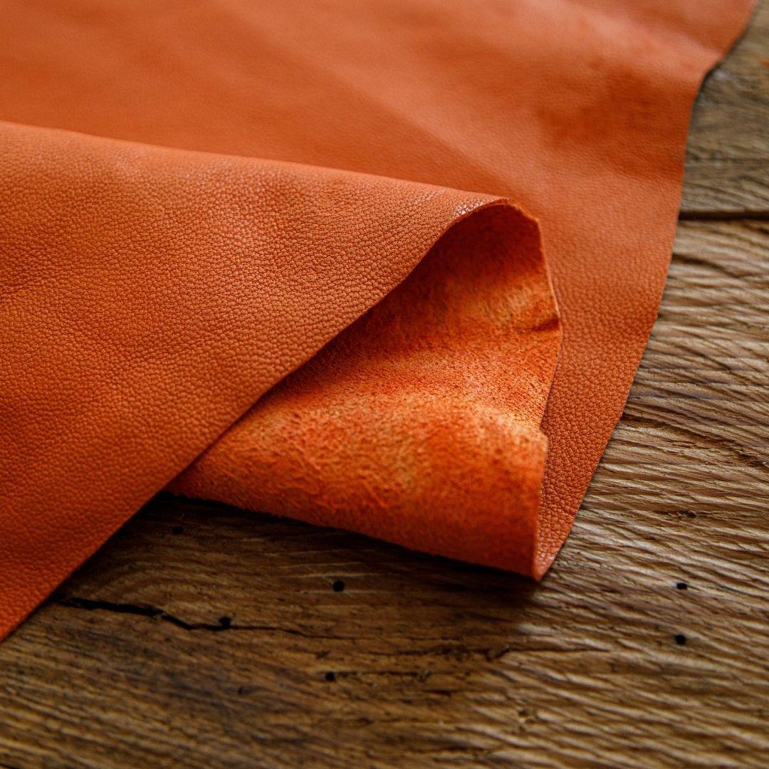 Rich orange cowhide leather with pebbled texture, ideal for crafting and upholstery projects.