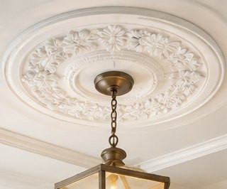 Ornate white ceiling medallion above a brass pendant lantern