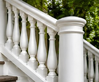 White porch handrail with turned balusters and a newel post