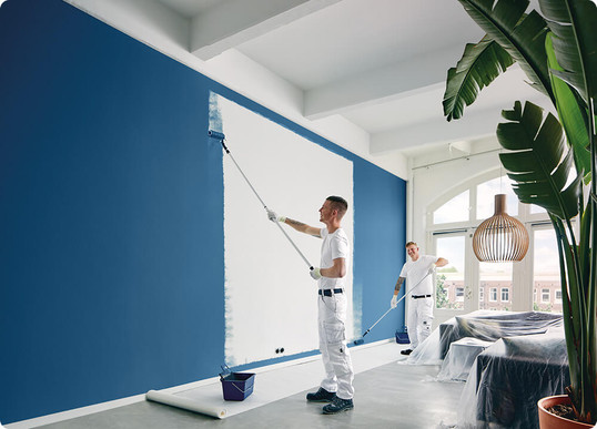 Een binnenmuur wordt door twee schilders behandeld met zeer goed dekkende blauwe muurverf