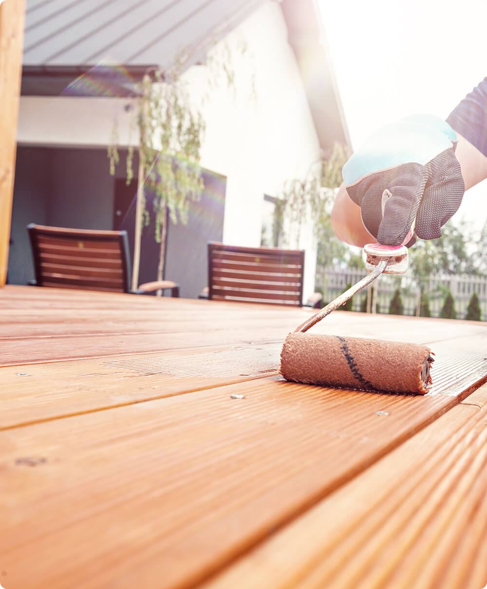 Bankirai olie wordt met een verfroller aangebracht op een houten tuintafel