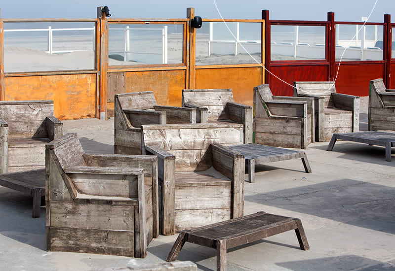 Verschillende steigerhouten stoelen op het strand.