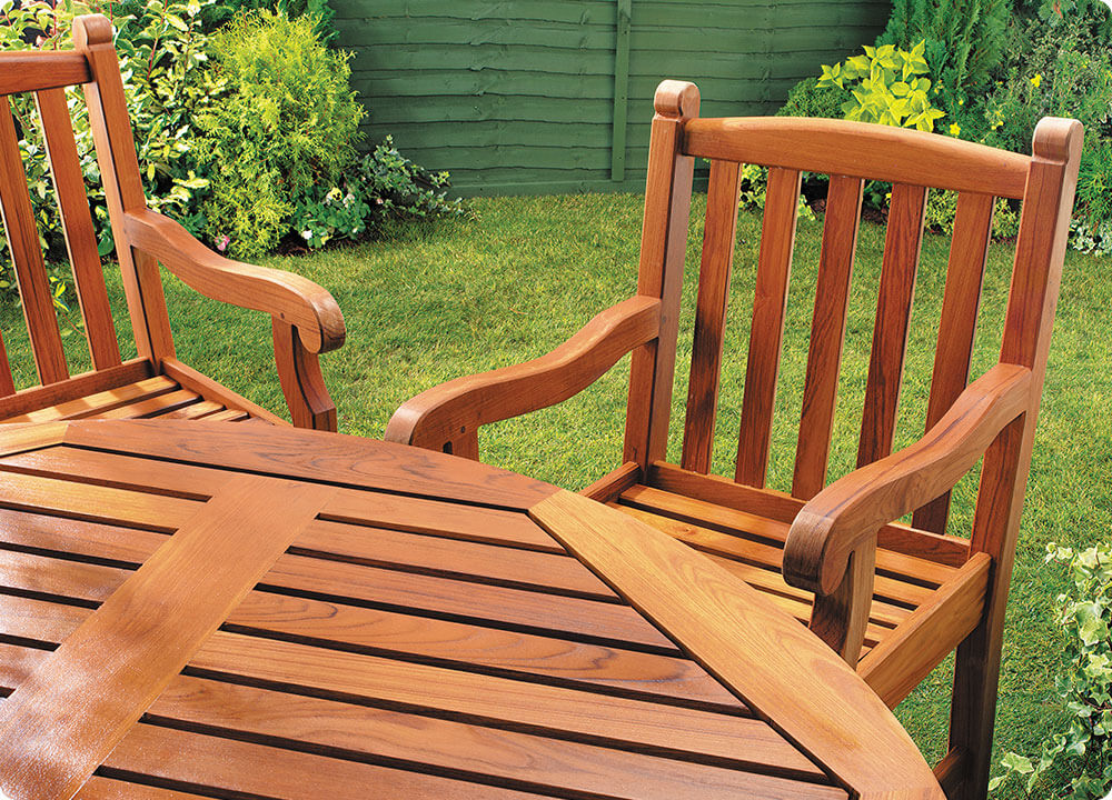 Stoelen en een tafel die behandeld zijn met transparante beits in een tuin met gras