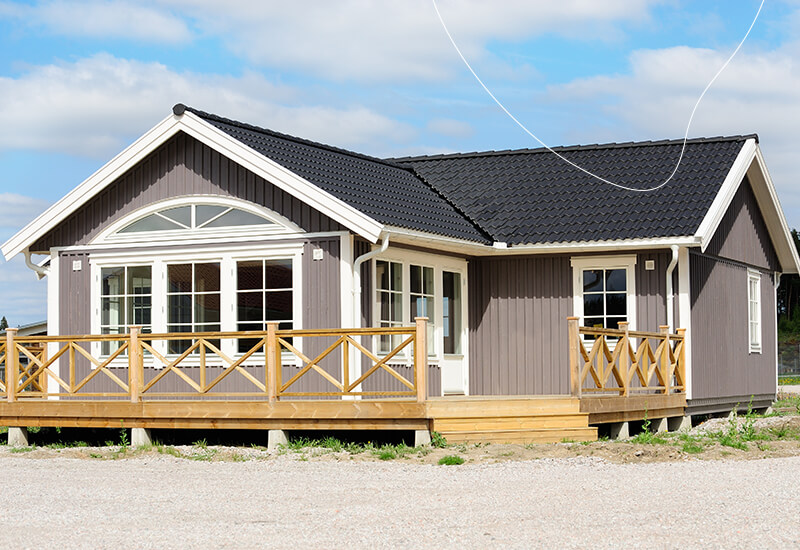 Een vakantiehuisje met grijze gevels, en zwart geschilderde dakpannen.