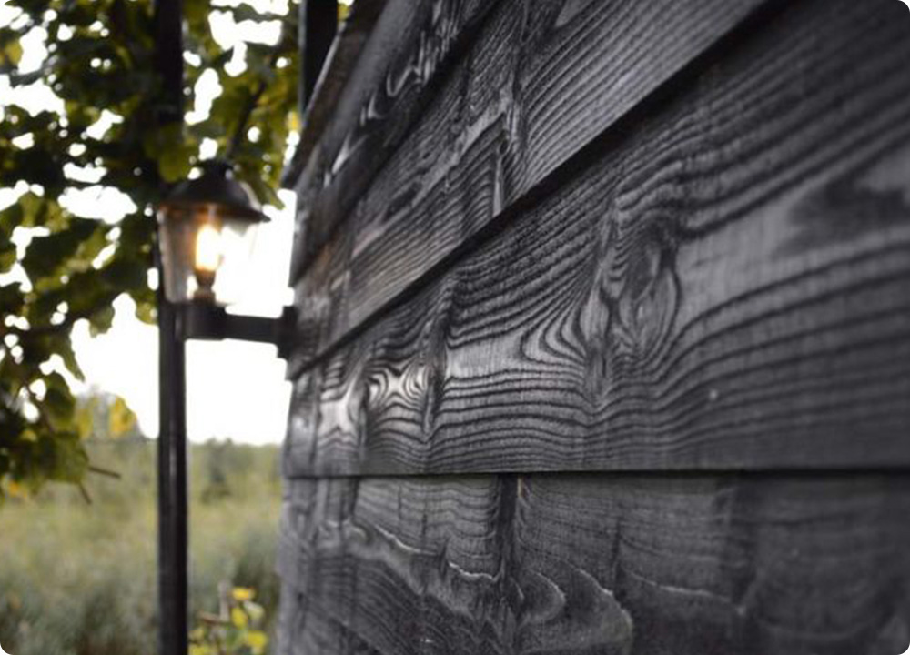 Een houten schutting die behandeld is met donkere dekkende beits