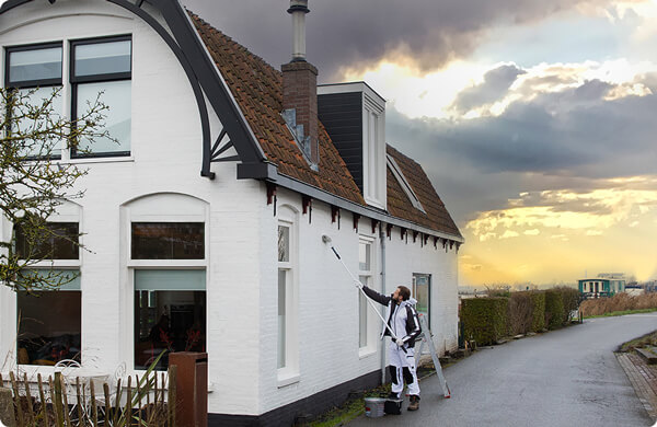 Een schilder schildert de muur van een woning met witte Sikkens buitenmuurverf