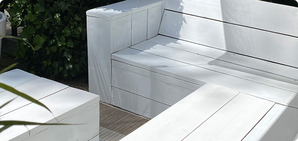 Houten tuinset met een hoekbank en een tafel, die behandeld zijn met dekkende white wash beits