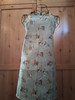Handmade green Peter Rabbit apron showcasing classic storybook woodland scenes with coordinating straps and a cozy vintage feel