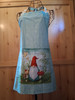 Handmade blue‑green apron with a 10.5‑inch square gnome pocket and coordinating gnome‑pattern neck loop and waist ties