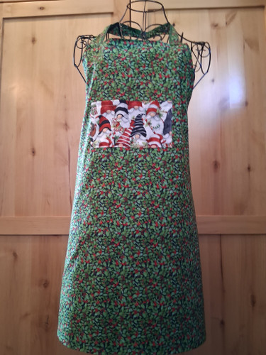 Handmade Christmas apron featuring holly fabric, a 7×4 gnome pocket, and white gnome waist ties