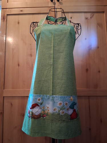 Handmade meadow‑themed apron with green fabric, a wide gnome pocket panel, and matching green ties