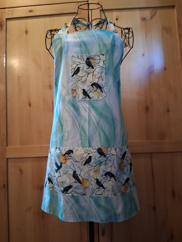 Handmade soft green apron with marbled background and two crow‑pattern pockets, including matching head loop and waist ties