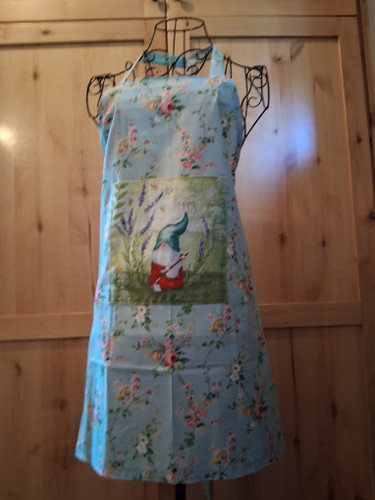 Handmade blue‑green apron decorated with pink and white flowers and an 8 × 8 gnome‑and‑lavender pocket, coordinating neck loop and waist ties