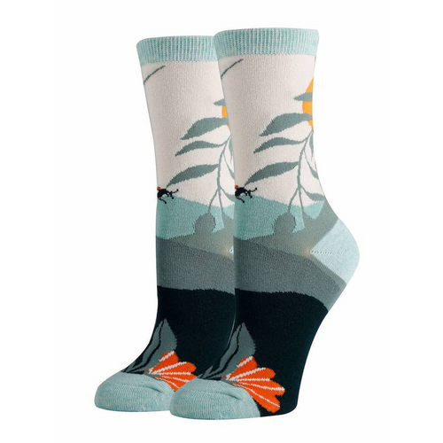 A pair of crew socks made of premium cotton with a design featuring light gray as the dominant color, leaf patterns in a shade of green with subtle orange accents, and a solid black block around the foot transitioning into a teal toe and heel section.