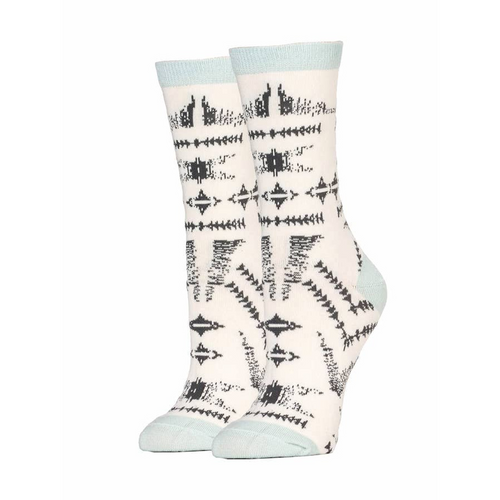 A pair of crew-length socks made from premium cotton, featuring a unique black and white pattern with tribal-inspired designs. The socks have a pale blue band at the top, a seamless toe area, and a matching pale blue heel and toe. The background is solid white.