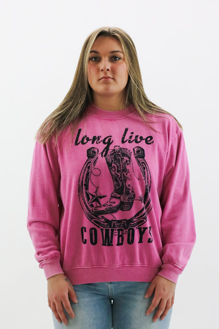 Model showcasing a new arrival for spring, a vibrant pink crewneck sweatshirt with a bold 'long live cowboys' graphic, available at Trendy Threads Boutique.