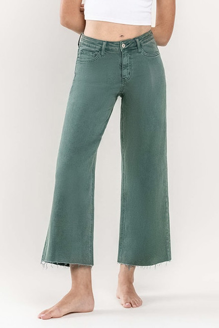 A close-up view of the Paige Cropped Jeans by Vervet, showing the dark green colored denim, wide leg cropped fit, and button/zip closure, styled with a simple white top.