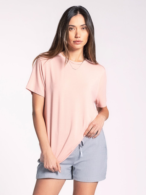 A woman in a casual pose wearing the Kim Tee by Thread & Supply, showcasing the soft peach color, classic crew neckline, and relaxed fit for all-day comfort.