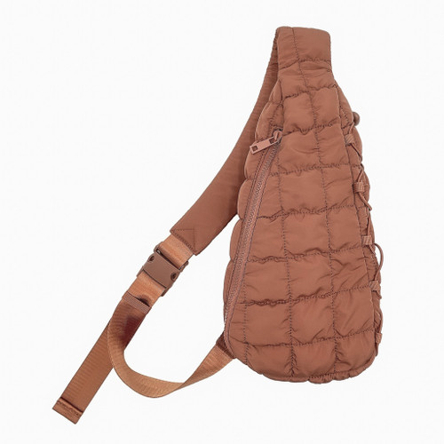 A stylish caramel brown quilted sling bag featuring a full zip closure and an adjustable nylon strap with a buckle. The bag has a textured surface, measuring approximately 14 inches high, 8 inches wide, and 4 inches deep. It's fully lined with an inside zip pocket and an additional open pocket, crafted from 100% polyester.