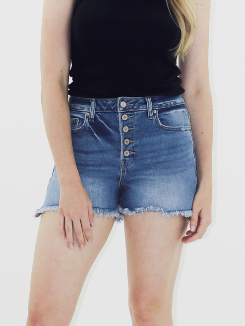 Woman wearing a black tank top and light blue denim shorts with button front and frayed hem.