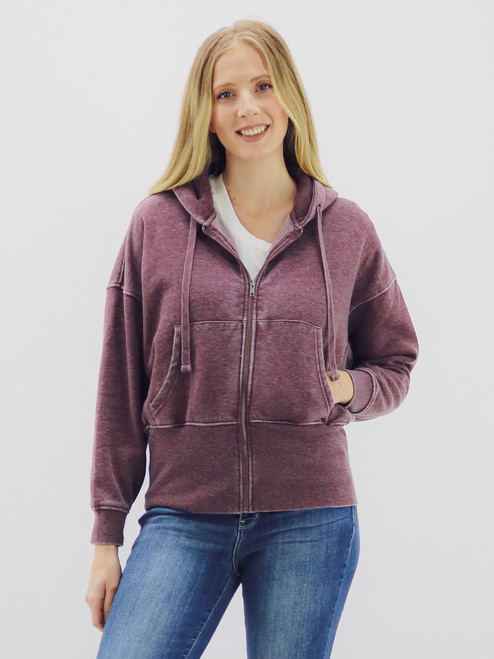 Model wearing a soft, mineral-washed plum hooded sweatshirt with a zip front, styled casually with a white tee and blue jeans. Model wearing a soft, mineral-washed plum hooded sweatshirt with a zip front, styled casually with a white tee and blue jeans.